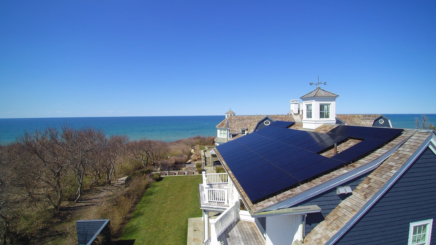 Aerial drone view of a residential home with a full rooftop solar panel array visible from above