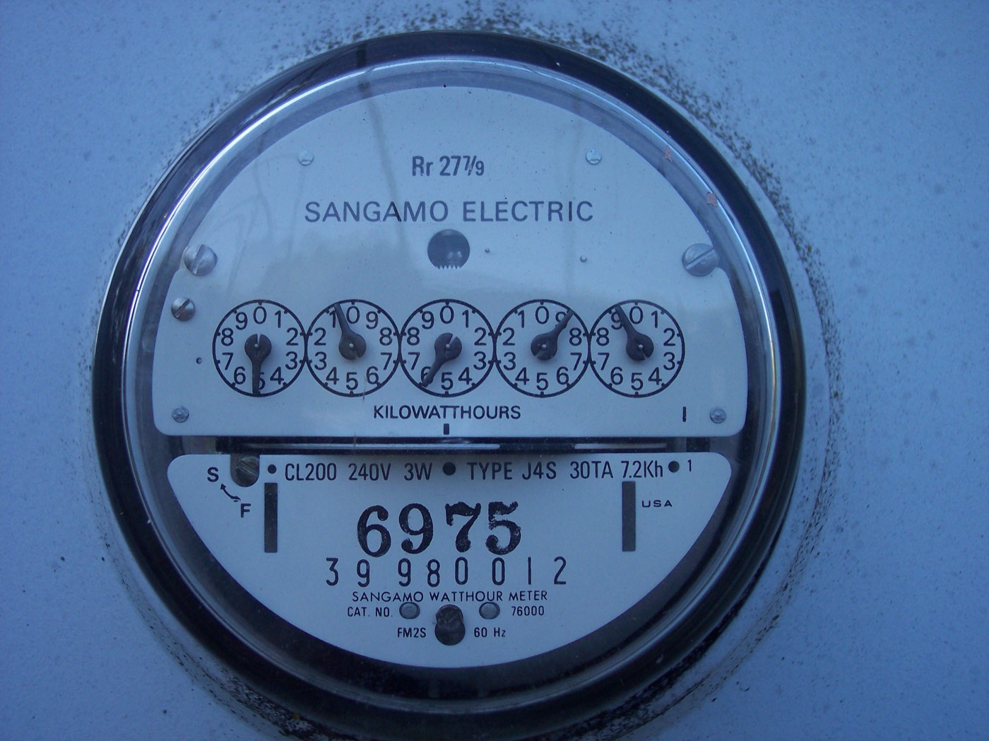 Close-up of a dial-style electric utility meter mounted on the side of a house, the kind used to track net metering