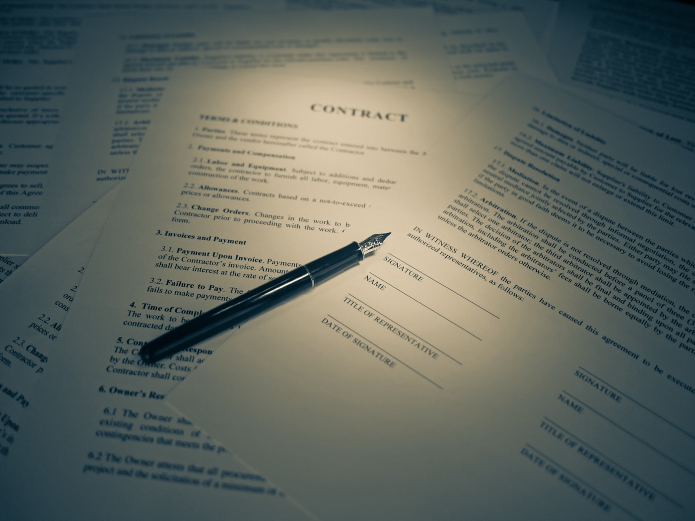A stack of legal financing paperwork on a desk with a pen resting on top
