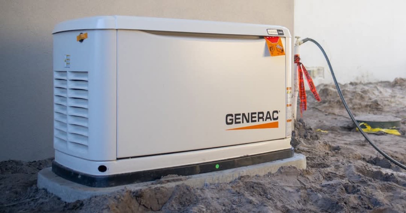 An outdoor whole-house standby generator unit installed on a concrete pad beside a home