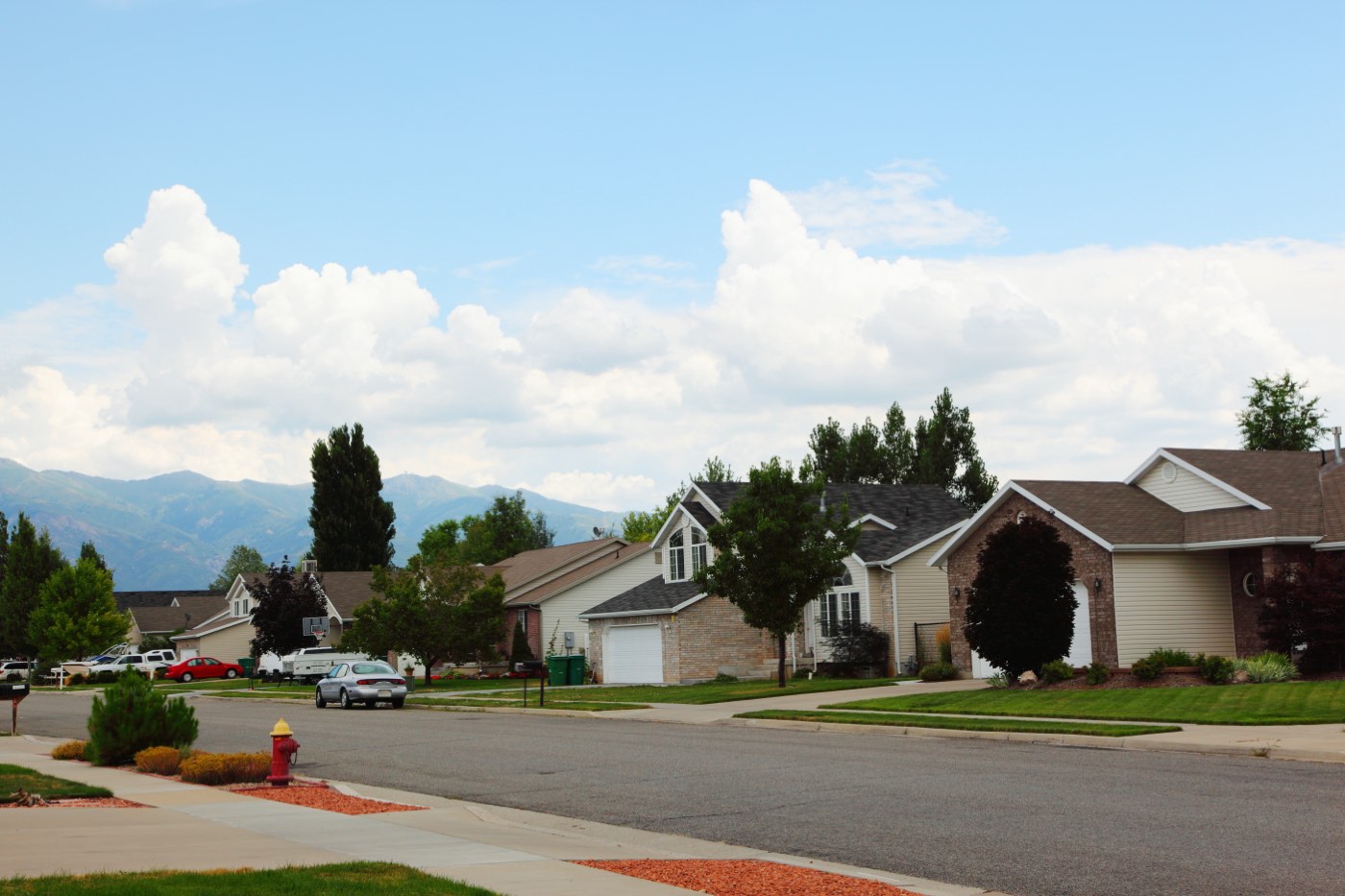 A suburban street in Layton, Utah lined with single-family homes and driveways, typical of an HOA-governed neighborhood