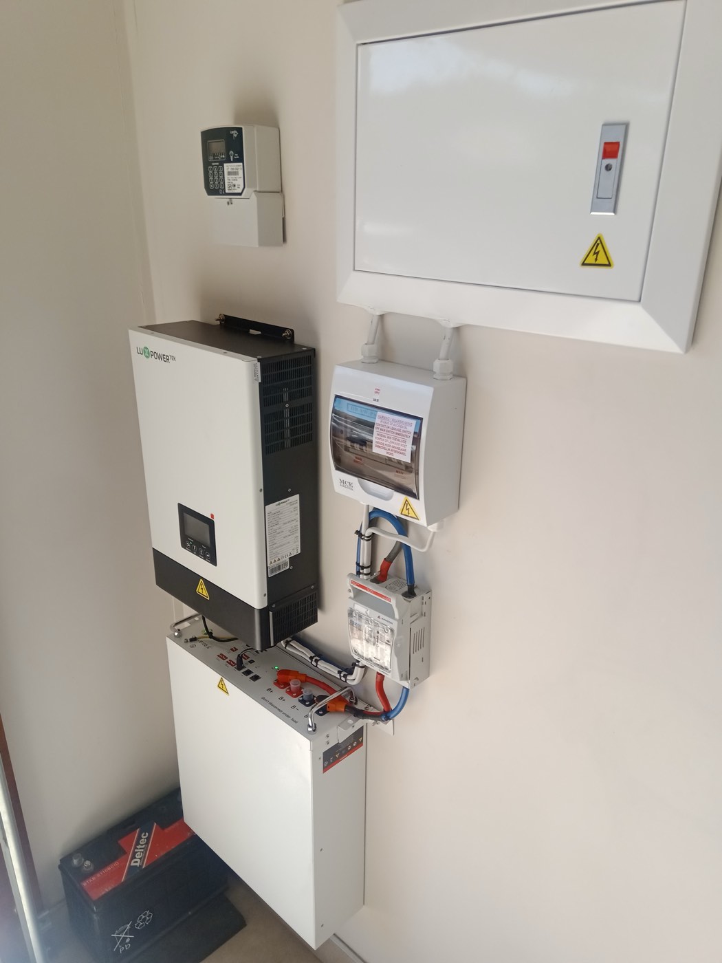A lithium home battery unit and hybrid inverter mounted together in a utility closet