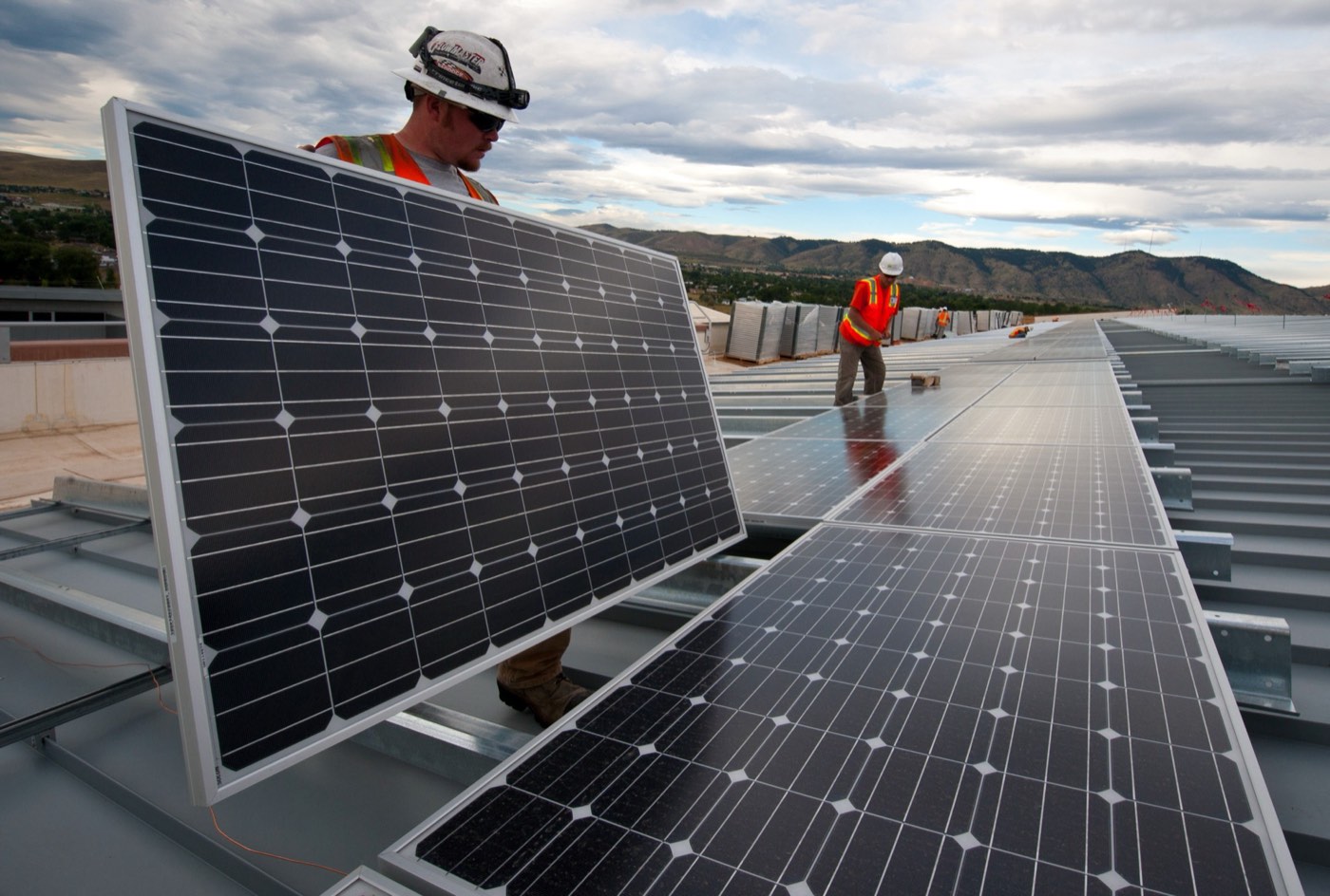 Two workers installing photovoltaic solar panels on a rooftop