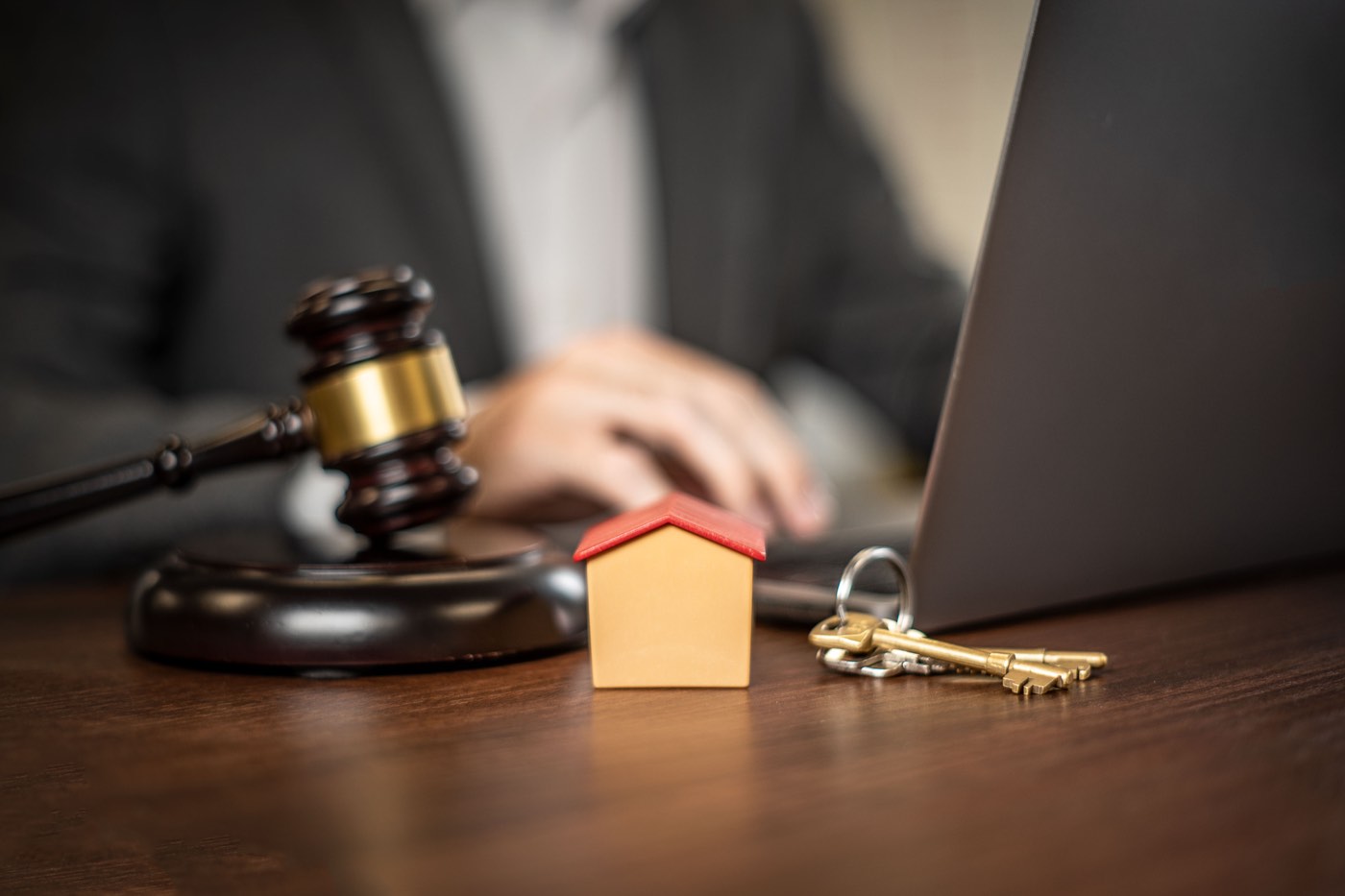 A gavel and house keys resting on a desk, symbolizing the legal agreements involved in property and home financing contracts