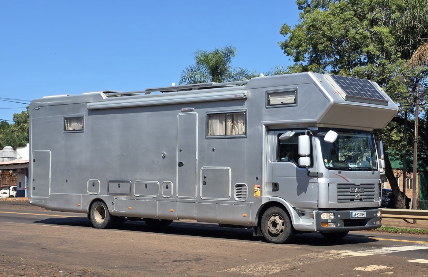 A large truck-based motorhome with a rooftop solar panel visible above the cab-over sleeping area
