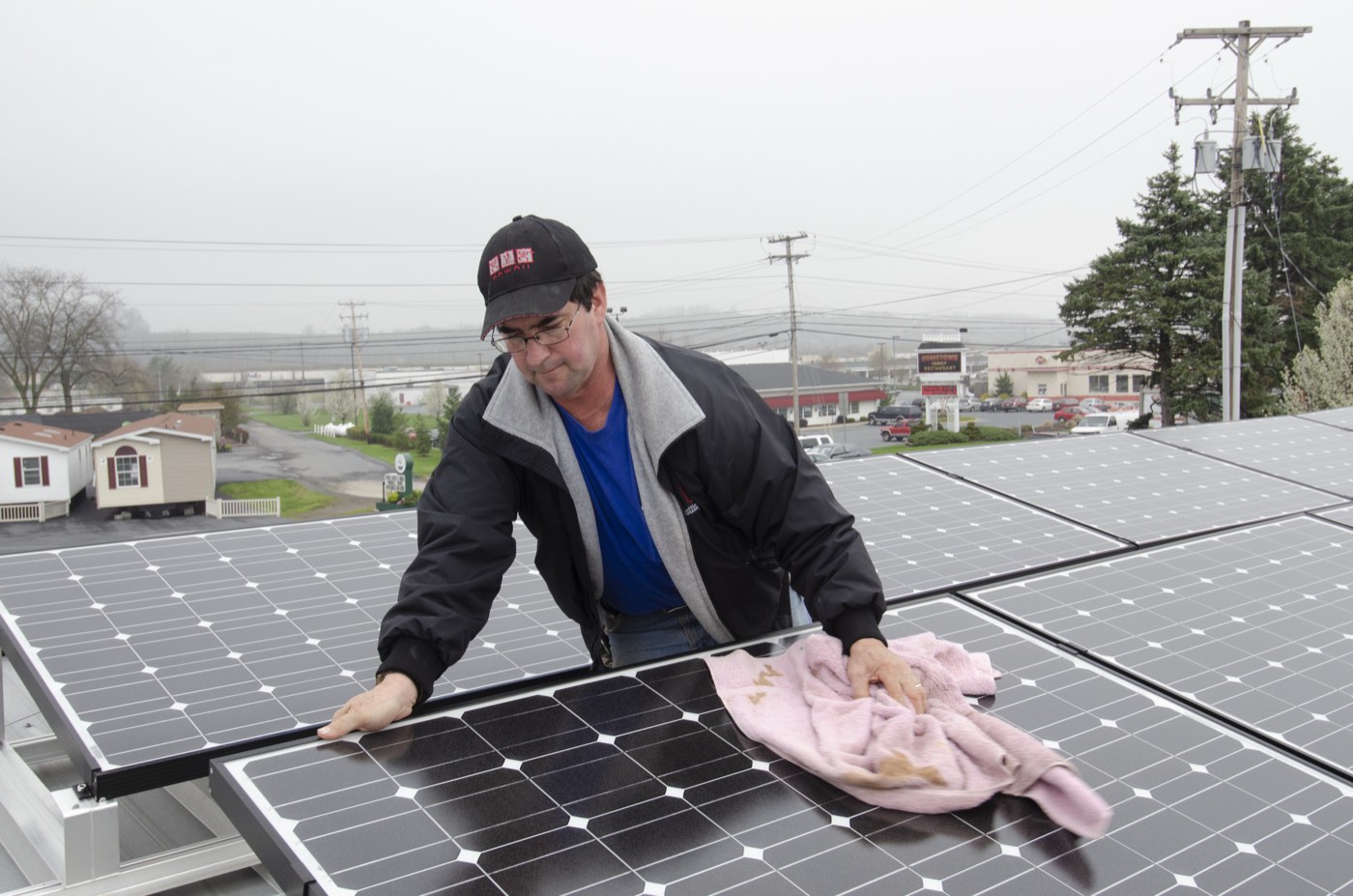 A worker wiping down rooftop photovoltaic panels to maintain peak performance