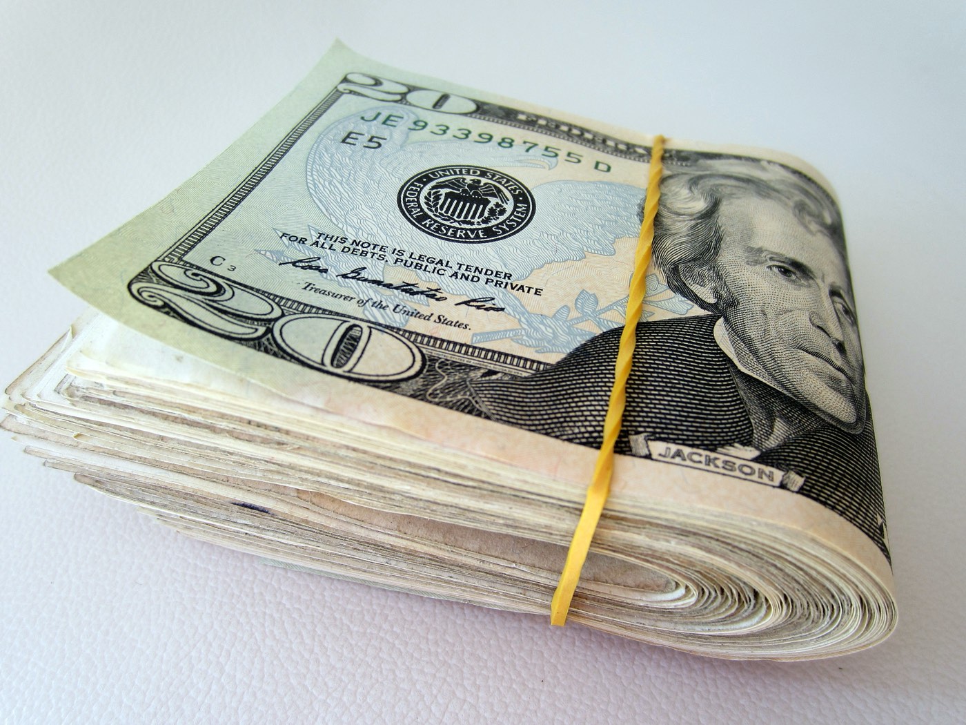 A rubber-banded stack of twenty-dollar bills on a plain surface, representing upfront investment cost